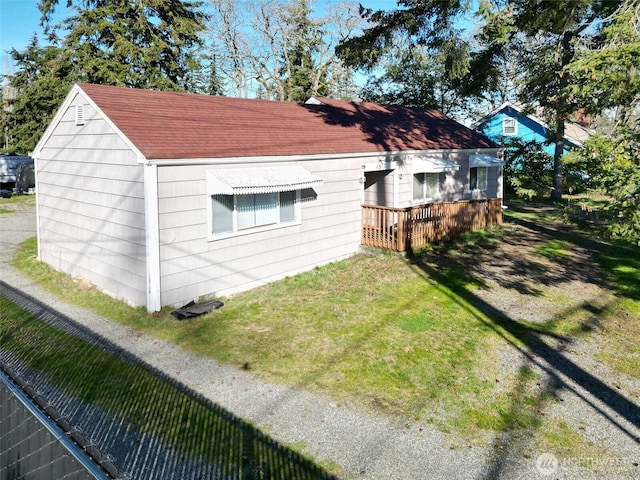 view of side of home with roof with shingles and a lawn