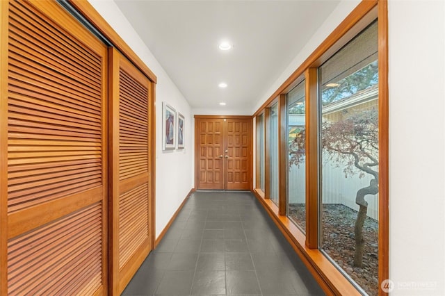 hallway featuring recessed lighting, dark tile patterned floors, and baseboards