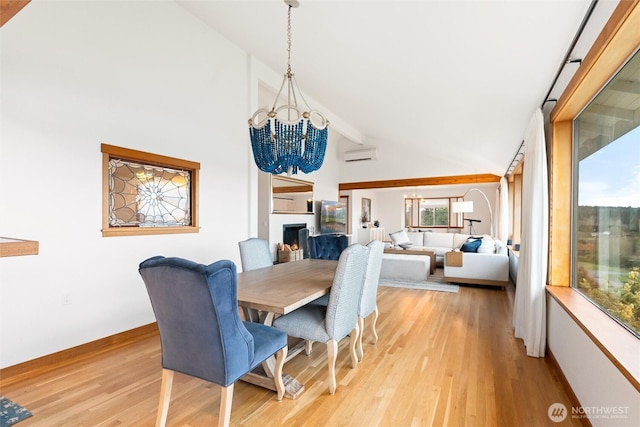 dining space with high vaulted ceiling, light wood-style flooring, a notable chandelier, a fireplace, and an AC wall unit