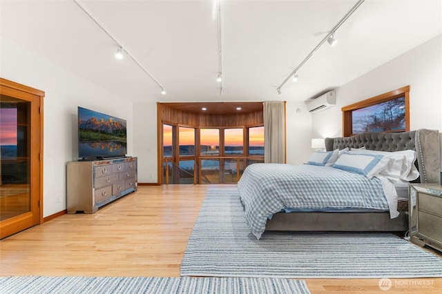 bedroom featuring light wood-style flooring, track lighting, and an AC wall unit