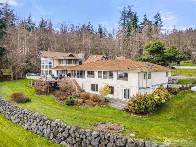 back of property with a lawn, a chimney, a wooden deck, and stairs