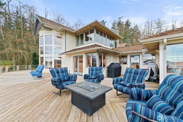 wooden deck with an outdoor living space, grilling area, and french doors