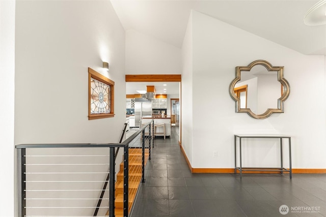 hall featuring high vaulted ceiling, an upstairs landing, and baseboards