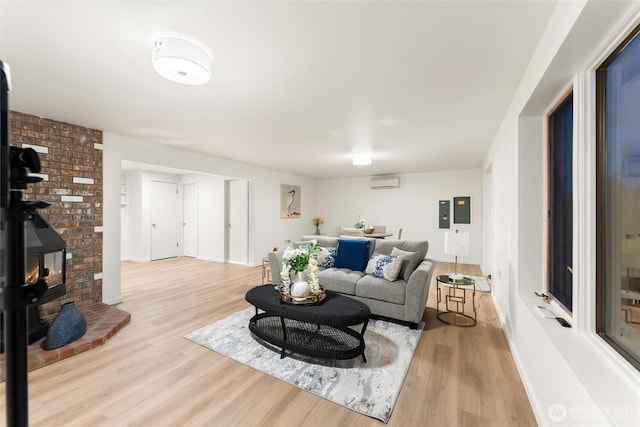 living room with an AC wall unit, baseboards, light wood-style flooring, and a wood stove