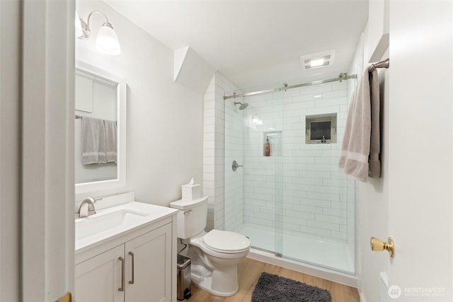 bathroom featuring vanity, wood finished floors, a shower stall, and toilet