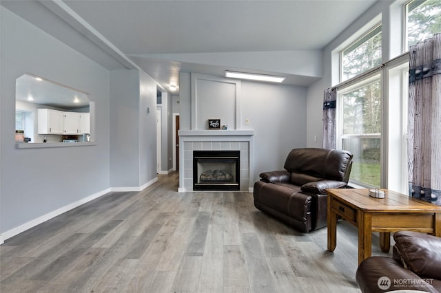 sitting room with light wood-type flooring, a tile fireplace, and baseboards