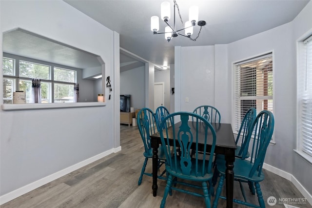 dining space featuring a chandelier, baseboards, and wood finished floors