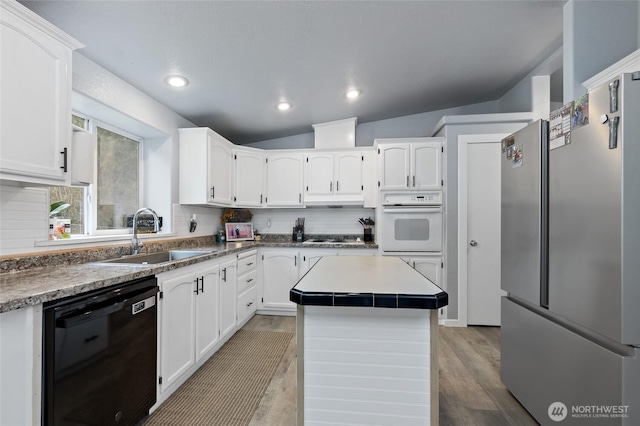 kitchen featuring a sink, white cabinetry, black dishwasher, freestanding refrigerator, and decorative backsplash