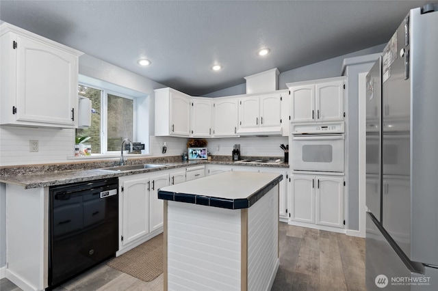 kitchen featuring dishwasher, white oven, stovetop, white cabinetry, and a sink