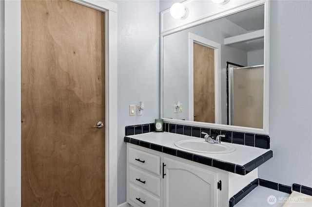 bathroom featuring a shower with door and vanity