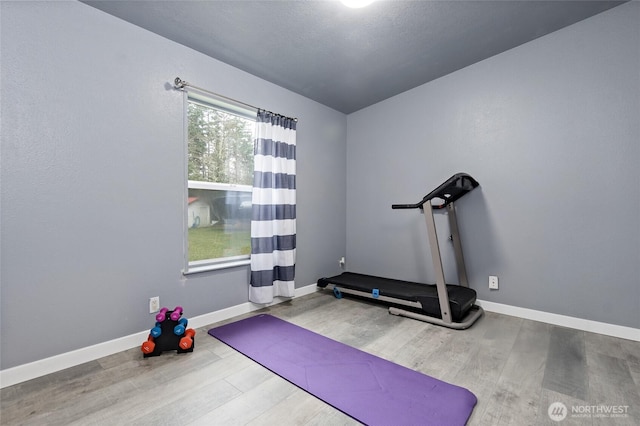 workout area featuring baseboards and wood finished floors