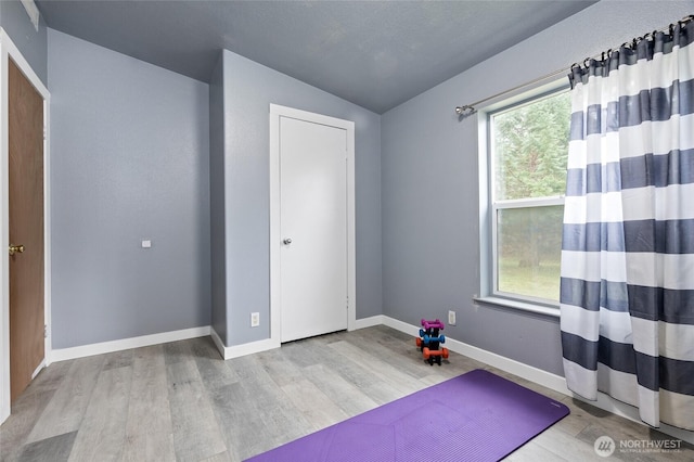 exercise room featuring wood finished floors and baseboards