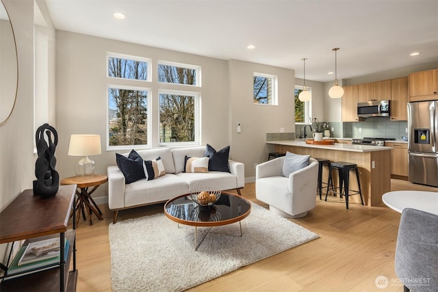 living area with recessed lighting, baseboards, and light wood finished floors