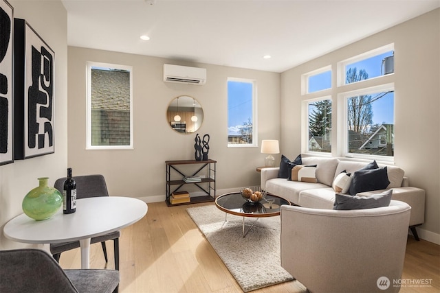 living area featuring light wood-type flooring, a wall unit AC, and baseboards