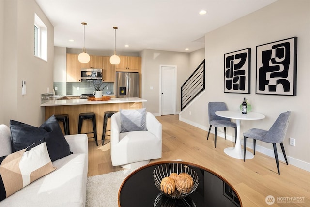 living area featuring light wood finished floors, stairway, recessed lighting, and baseboards