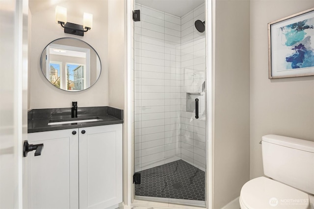 bathroom featuring a shower stall, toilet, and vanity