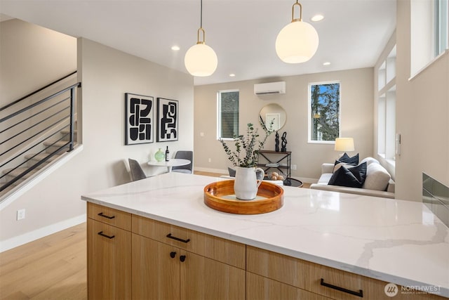 kitchen featuring open floor plan, an AC wall unit, light stone counters, and recessed lighting