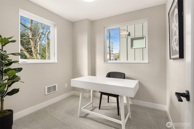 carpeted office featuring a healthy amount of sunlight, baseboards, and visible vents