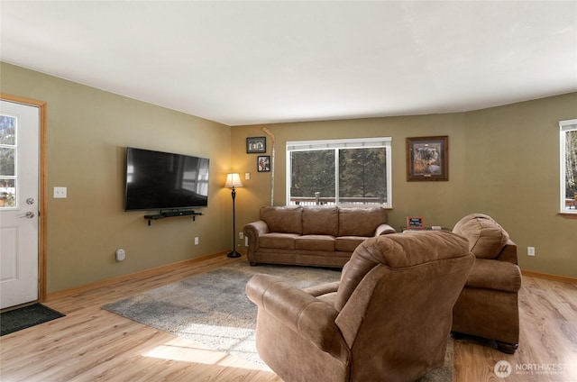 living area with plenty of natural light, baseboards, and wood finished floors