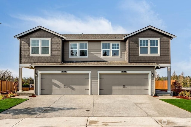 view of front facade featuring concrete driveway, fence, and an attached garage