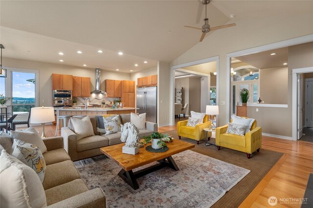 living area featuring a ceiling fan, baseboards, recessed lighting, vaulted ceiling, and light wood-style floors