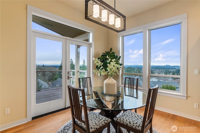 dining room with baseboards, light wood-style floors, and a healthy amount of sunlight