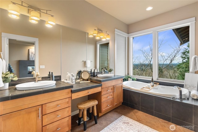 bathroom with tile patterned floors, a garden tub, and vanity