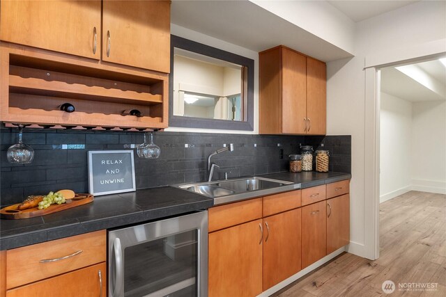 kitchen featuring beverage cooler, open shelves, a sink, light wood-type flooring, and backsplash