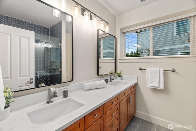 bathroom featuring a sink, baseboards, double vanity, and a shower stall