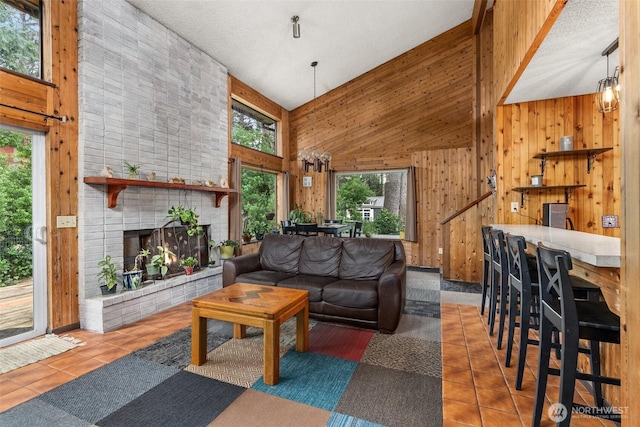 living area with wood walls, tile patterned flooring, and a brick fireplace