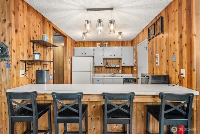 kitchen with open shelves, stainless steel appliances, a sink, a textured ceiling, and a peninsula