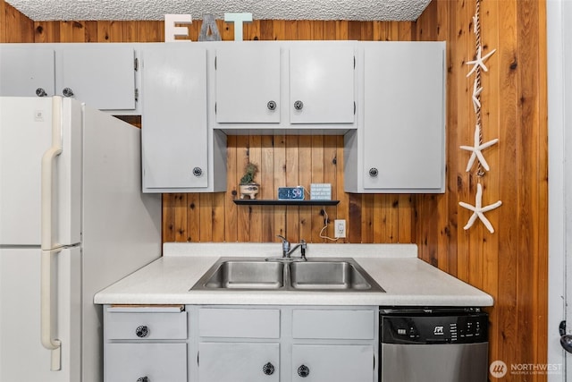 kitchen with light countertops, freestanding refrigerator, white cabinets, a sink, and dishwasher