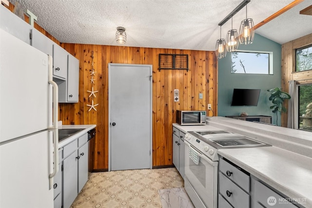 kitchen with white appliances, light countertops, wooden walls, and a textured ceiling