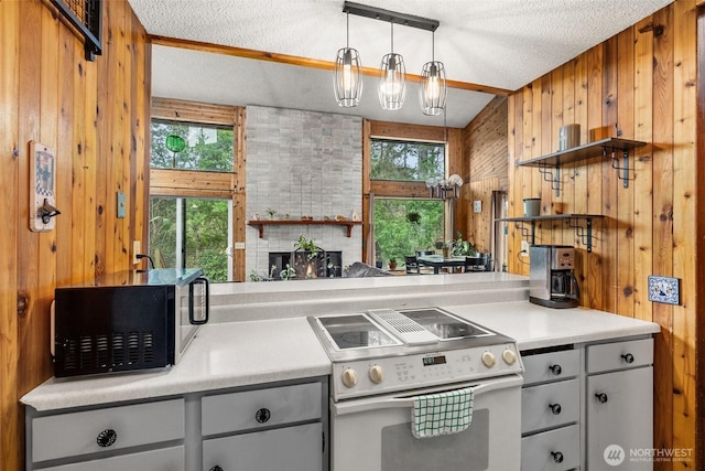 kitchen with wooden walls, light countertops, a textured ceiling, a fireplace, and white range with electric cooktop