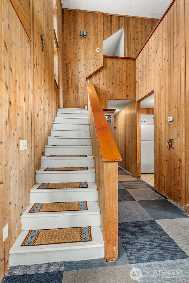 stairs with carpet floors, washer / clothes dryer, and wood walls