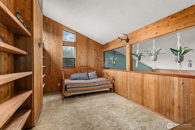 carpeted bedroom with vaulted ceiling, wooden walls, and a textured ceiling