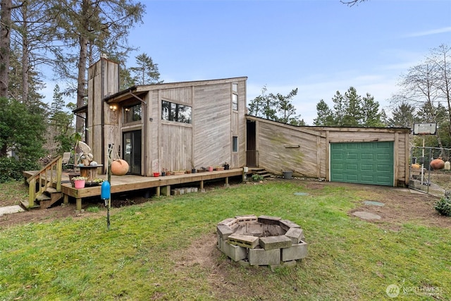 view of outbuilding with a garage, an outdoor fire pit, and driveway