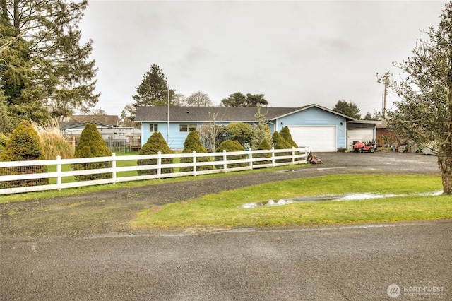 ranch-style home featuring driveway, a fenced front yard, a garage, and a front yard