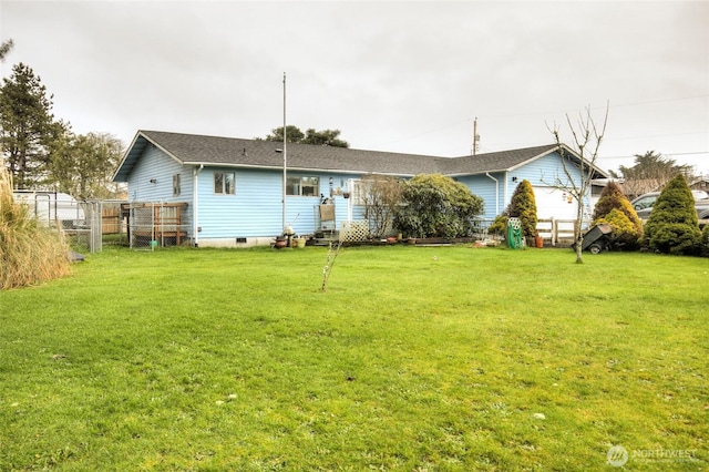 rear view of property featuring entry steps, a lawn, and fence