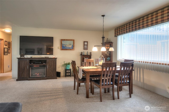 dining space featuring a glass covered fireplace and light carpet