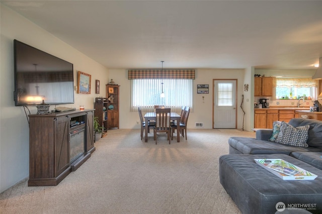 living room featuring visible vents, light colored carpet, and a healthy amount of sunlight