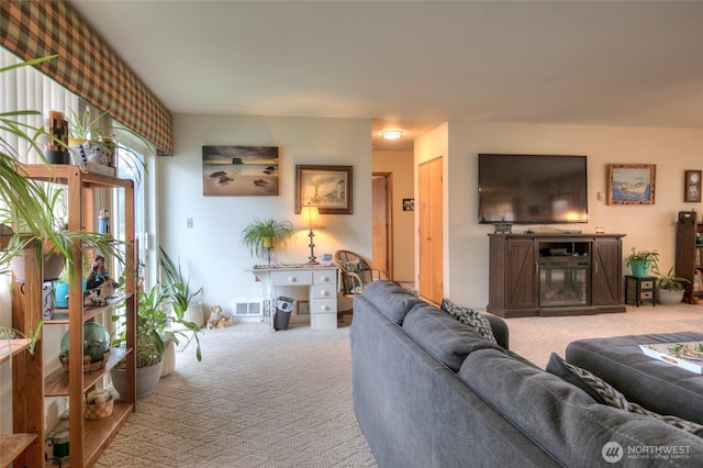 carpeted living room with a glass covered fireplace and visible vents