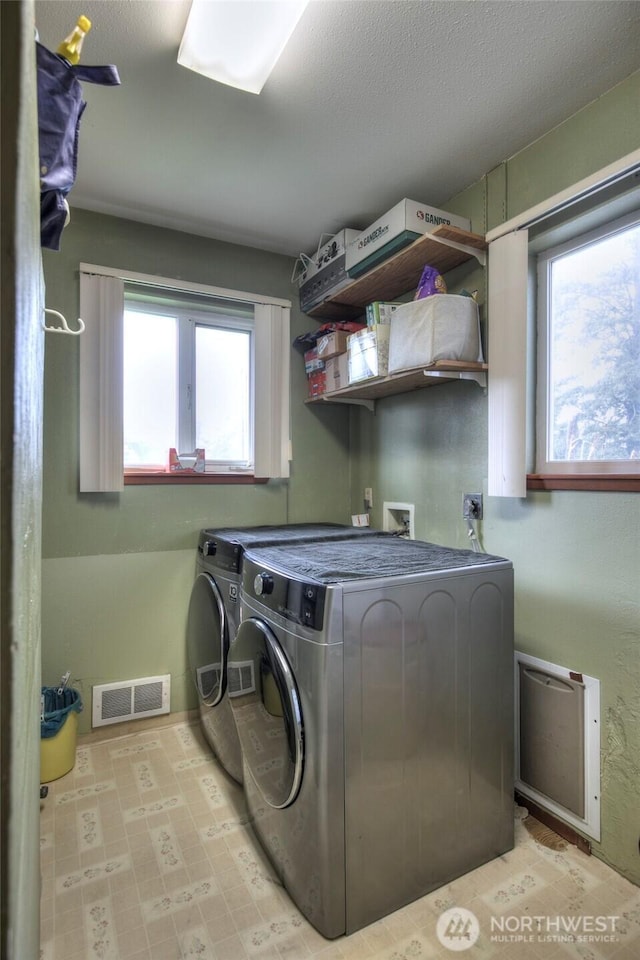 laundry room featuring a textured ceiling, laundry area, washing machine and dryer, and visible vents