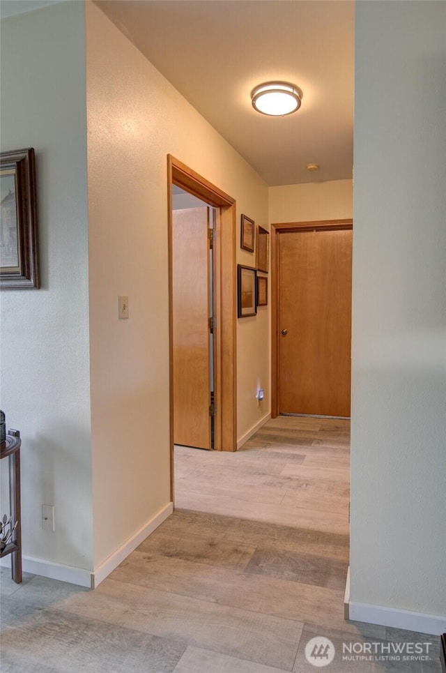 hallway with baseboards and light wood-style floors