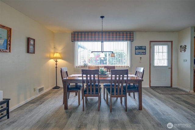 dining room featuring baseboards, visible vents, and wood finished floors