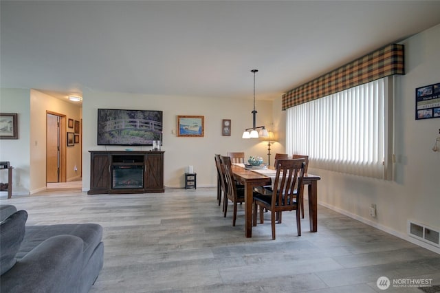 dining room with light wood finished floors, baseboards, and visible vents
