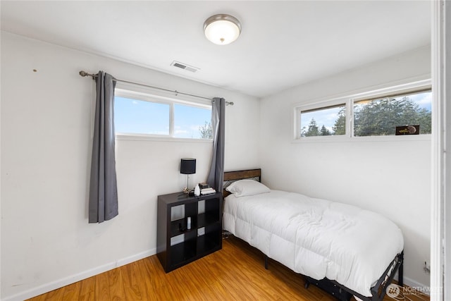 bedroom featuring wood finished floors, visible vents, and baseboards