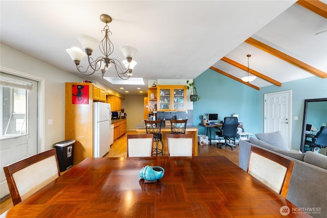 dining area with lofted ceiling with beams, light wood-style flooring, and a chandelier