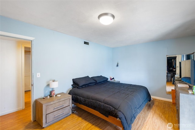 bedroom with light wood-type flooring, baseboards, and visible vents