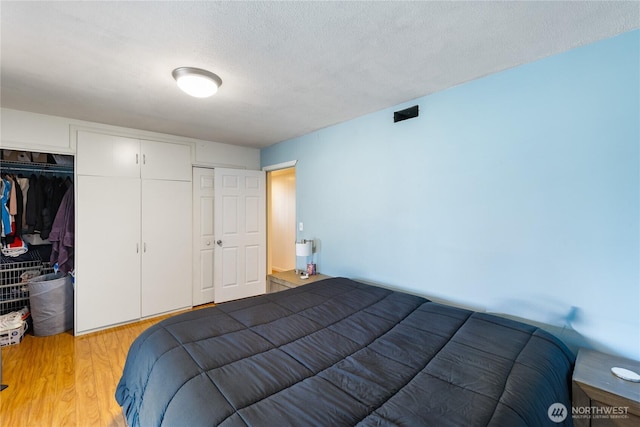 bedroom featuring a textured ceiling, a closet, and light wood-style flooring